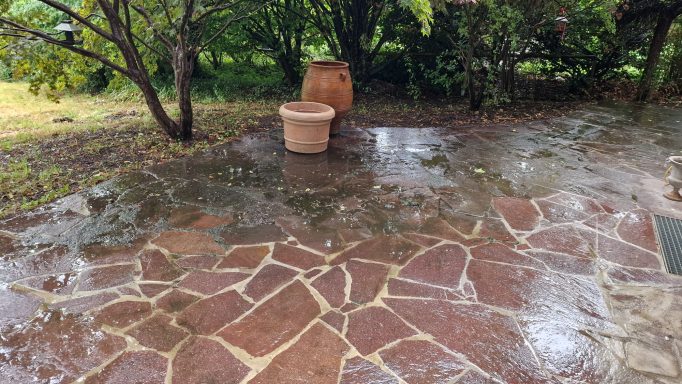 Teilreinigung einer Terrasse in Peißenberg – ein Bereich mit Hochdruck gereinigt, der andere noch verschmutzt.